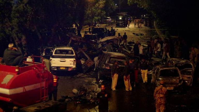 Police officers and paramilitary soldiers gather near the wreckage of vehicles after an explosion near Jinnah International Airport in Karachi, Pakistan October 6, 2024. - REUTERSPIX