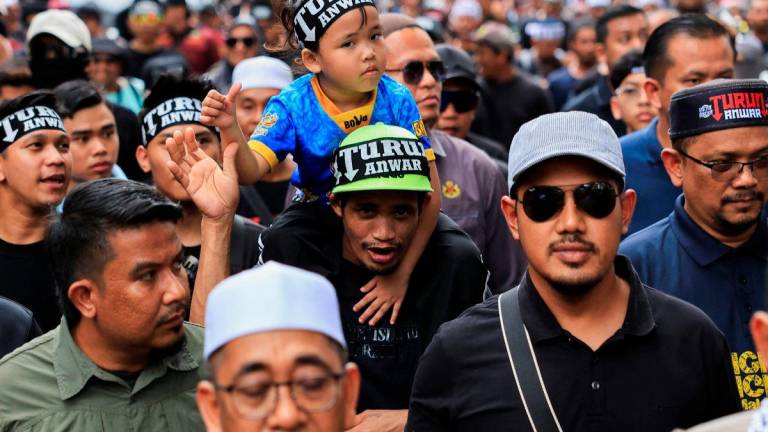 People wearing headbands with the slogan ‘TURUN ANWAR’, which means ‘Step down, Anwar’, march during a protest calling for Malaysian Prime Minister Anwar Ibrahim to resign in Kuala Lumpur, Malaysia July 26, 2025. REUTERS/Hasnoor Hussain