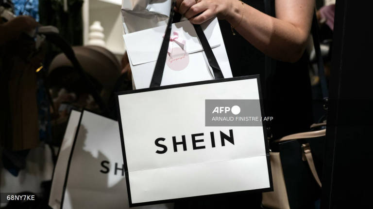 (FILES) A customer holds her bags as she leaves a pop-up store of the Chinese-founded fast fashion brand Shein, in Dijon on June 26, 2025. Italy's competition watchdog said on August 4, 2025, it has fined the company responsible for Shein's websites in Europe one million euros ($1.15 million) for false and confusing claims about the e-commerce giant's efforts to be environmentally green. (Photo by ARNAUD FINISTRE / AFP)