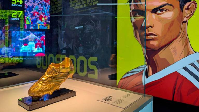 Cristiano Ronaldo’s Golden Boot trophy is seen on display beside a portrait of the footballer during the opening of the CR7 LIFE Museum in Hong Kong on July 7, 2025. (Photo by Holmes CHAN / AFP)