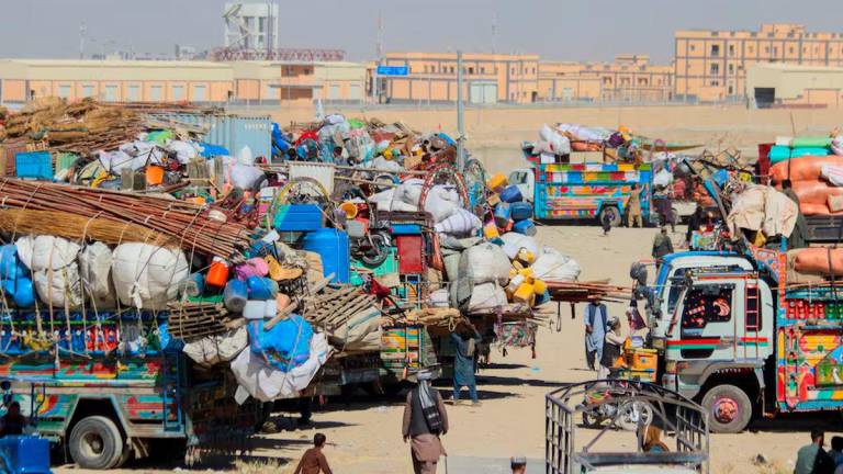 People walk past parked vehicles with belongings of Afghan citizens, as they head back to their country, after Pakistan closed border crossings with Afghanistan, following exchanges of fire between the forces of the two countries. REUTERS/Saeed Ali Achakzai