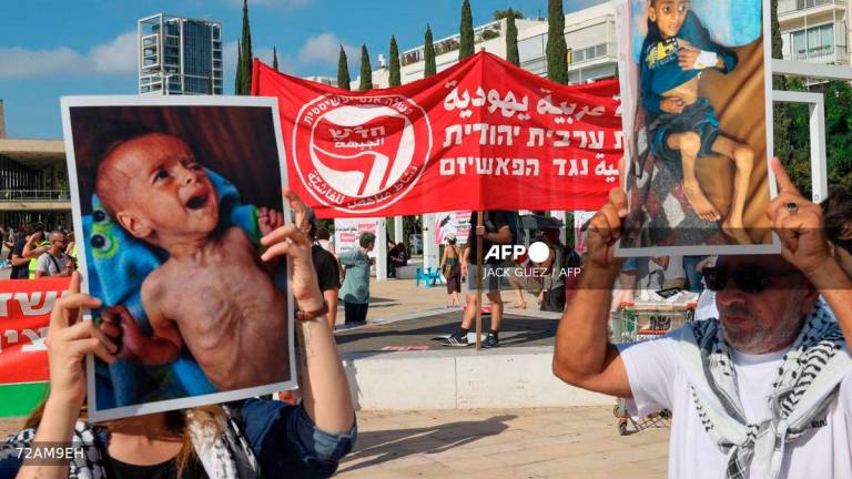 Arab-Israeli and Israeli left-wing activists hold photos of malnurished children during a protest at HaBima square in Tel Aviv, against the ongoing war and the catastrophic humanitarian situation in the Gaza Strip on August 23, 2025. - AFP