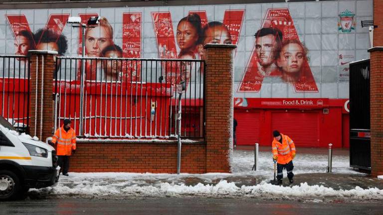 Workers clear snow outside the stadium before the match. Photo: Reuters