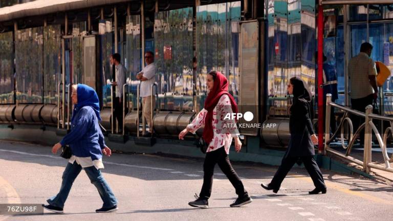 Iranian women walk in front of a public transportation station in Tehran on September 28, 2025. - AFPPIX