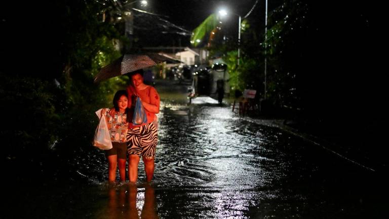 People wade through a flooded street following rain, intensified by Severe Tropical Storm Matmo, in Santa Lucia, Calumpit, Bulacan province, Philippines, October 3, 2025. - REUTERSPIX