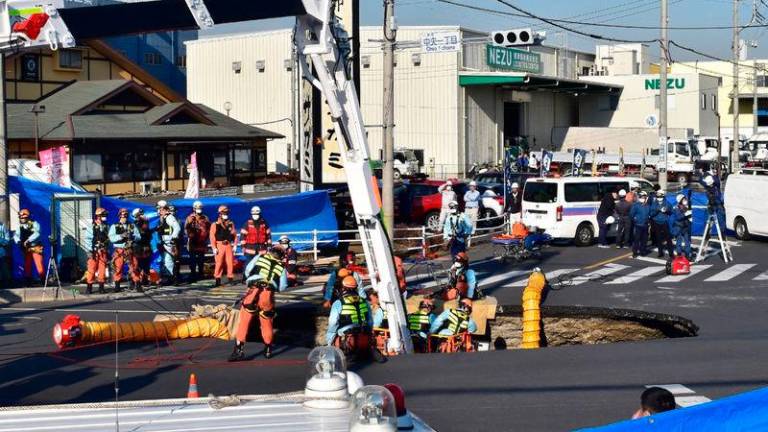 Firefighters work to rescue a truck driver after his vehicle was swallowed up by a sinkhole at a prefectural road intersection, in the city of Yashio, Saitama Prefecture - AFPpix