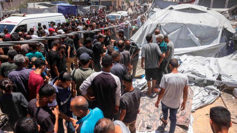 People check the site on an Israeli strike next to a tent housing displaced Palestinians, in Gaza City, on July 8, 2025. (Photo by BASHAR TALEB / AFP)