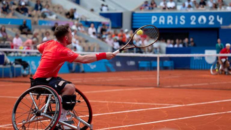 Britain's Alfie Hewett serves the ball next to his teammate Gordon Reid during the gold medal match against Japan's Takuya Miki and Tokito Oda in the Men's Doubles Wheelchair Tennis on the Court Philippe-Chatrier, at the Stade Roland-Garros, during the Paris 2024 Paralympics Games, on September 6, 2024. - AFPPIX