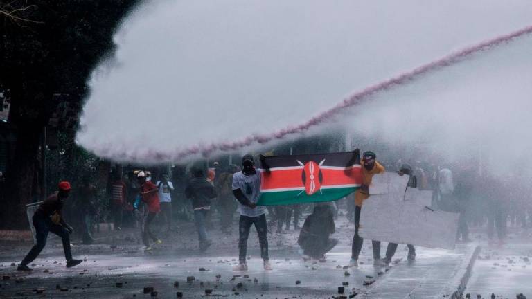 Protesters are caught by the jet of a Kenyan police water cannon in downtown Nairobi on June 25, 2025. (Photo by Kabir Dhanji / AFP)