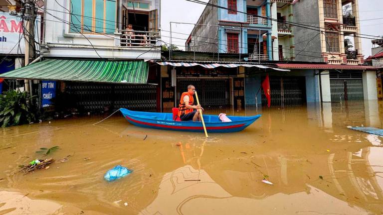 A man rows a canoe through waters past buildings in That Khe commune flooded after heavy rains caused by Typhoon Matmo in Lang Son province on October 8, 2025. (Photo by Anh TUC / AFP)