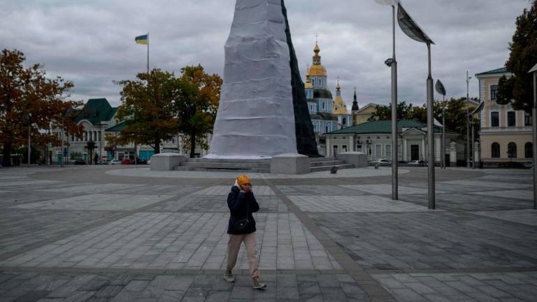 A pedestrian walks past the Independence Monument wrapped in a protective cover, in Kharkiv, eastern Ukraine on October 13, 2025. - AFPPIX