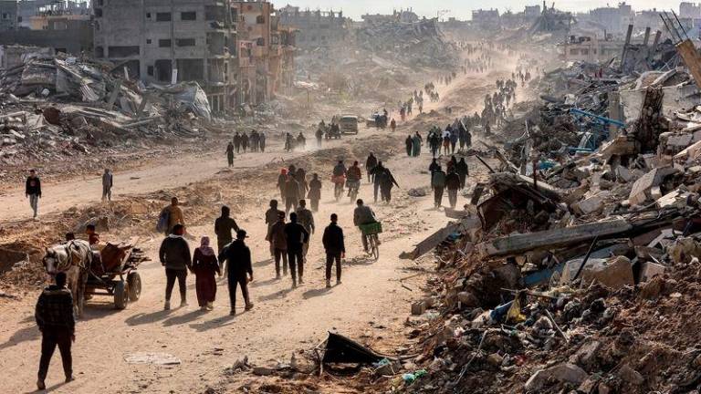 People walk past the rubble of collapsed buildings along Saftawi street in Jabalia in the northern Gaza Strip - REUTERSpix