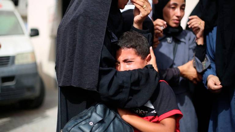 Palestinian mourners hug each other at the al-Aqsa Martyrs hospital in Deir el-Balah in the central Gaza Strip on July 1, 2025, following overnight Israeli strikes as the war between the Palestinian Hamas militant and Israel continues. (Photo by Eyad BABA / AFP)