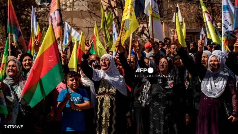 Syrian Kurds lift placards and flags during a rally calling for an autonomous administration and Kurdish rights in Syria's predominantly-Kurdish northeastern city of Qamishli on September 17, 2025. - AFP