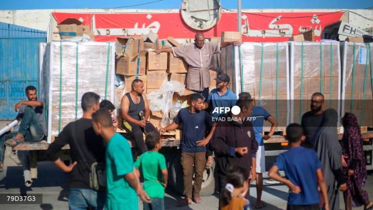 Displaced Palestinians gather around a truck to receive aid supplies that entered Gaza in the morning at the Nuseirat refugee camp in the central Gaza Strip, on October 20, 2025. (Photo by Eyad BABA / AFP)