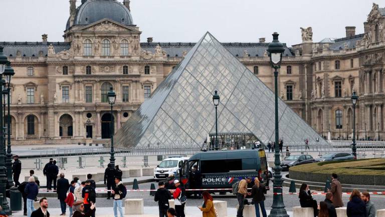 Police stand near the pyramid of the Louvre museum after reports of a robbery, in Paris, France, October 19, 2025. REUTERS/Gonzalo Fuentes