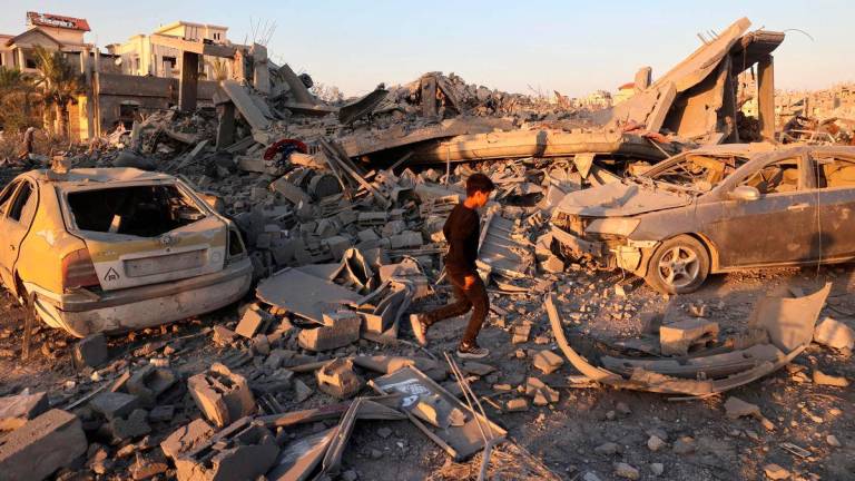 A Palestinian youth walks past the destruction of homes and buildings in the Al-Bureij camp in the central Gaza Strip after an Israeli strike, on June 27, 2025, amid the ongoing conflict between Israel and the Palestinian Hamas militant group. (Photo by Eyad BABA / AFP)
