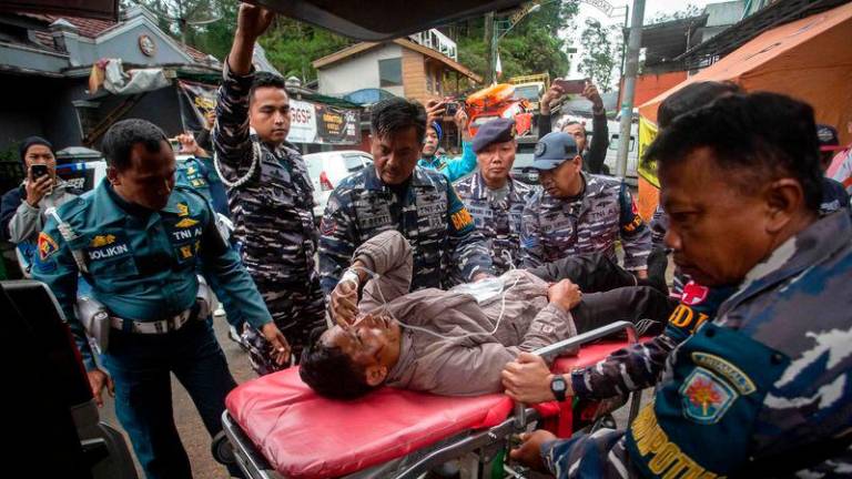 Rescue personnel transport a survivor, from the site of a landslide triggered by heavy rains, to a hospital in Mudal village, near Pekalongan city in Central Java - AFPpix