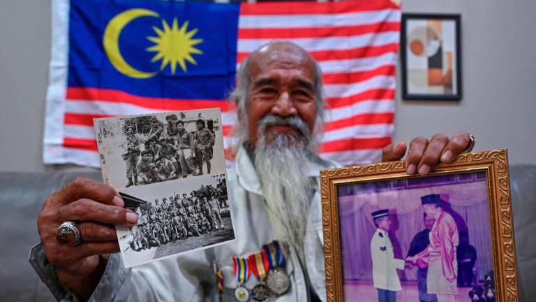 Former member of the first VAT 69 squad, Che Yak @ Embong Ngah, 77, shows a photo from his service when interviewed at the Marang District Police Headquarters (IPD) today. - BERNAMA
