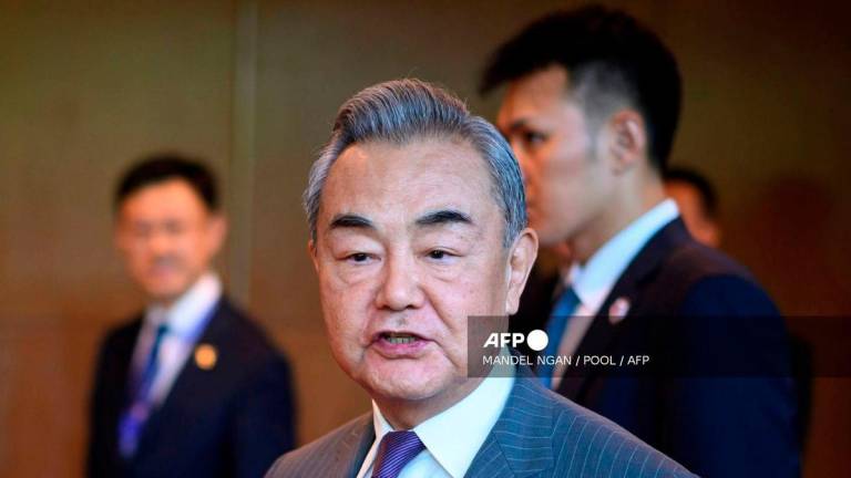 China's Foreign Minister Wang Yi speaks to the media as he walks between meetings during the 58th ASEAN Foreign Ministers’ meeting and related meetings at the Convention Centre in Kuala Lumpur on July 11, 2025. - POOL via AFP