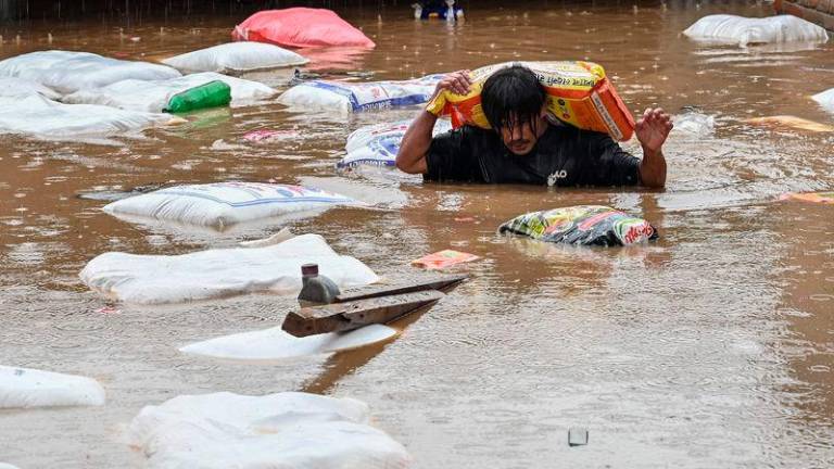 A man carrying a sack of flour wades through flood waters after the Bagmati River overflowed following heavy monsoon rains in Kathmandu - AFPpix