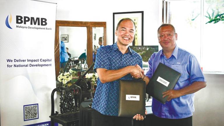 Wee (left) and Lau exchange documents after signing the Lundu Beach Resort financing agreement.