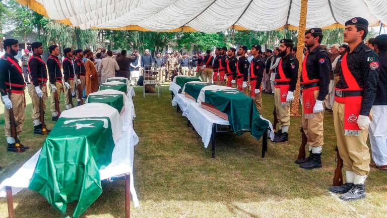 Policemen stand by the coffins of slain police personnel during a funeral ceremony at Dera Ismail Khan in Khyber Pakhtunkhwa province on October 11, 2025, a day after they were killed in a suicide bombing attack at a police training school. The Pakistani Taliban on October 11, claimed responsibility for deadly attacks in several northwestern districts that killed 20 security officials and three civilians. - AFP
