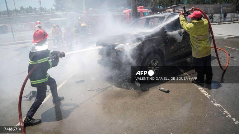 Firefighters extinguish a government vehicle set alight by university students protesting the parliament’s plan to buy 65 SUVs for lawmakers in Dili, East Timor, on September 16, 2025. (Photo by VALENTINO DARIELL DE SOUSA / AFP)