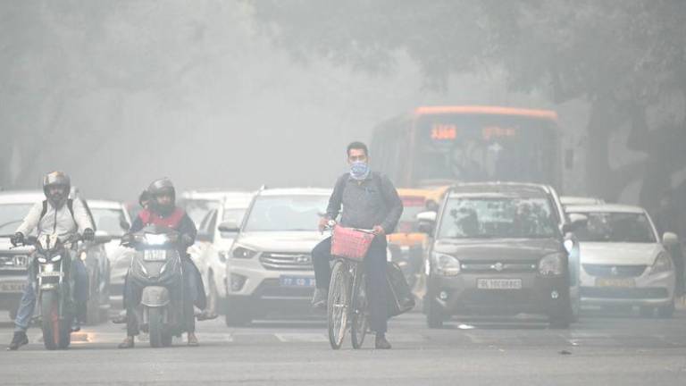 A cyclist with his face covered in cloth rides along a street on a cold smoggy morning in New Delhi - AFPpix