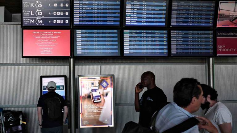Passengers look at the departures information board at Roissy Charles-de-Gaulle airport, outside Paris, on July 3, 2025. (Photo by Thibaud MORITZ / AFP)