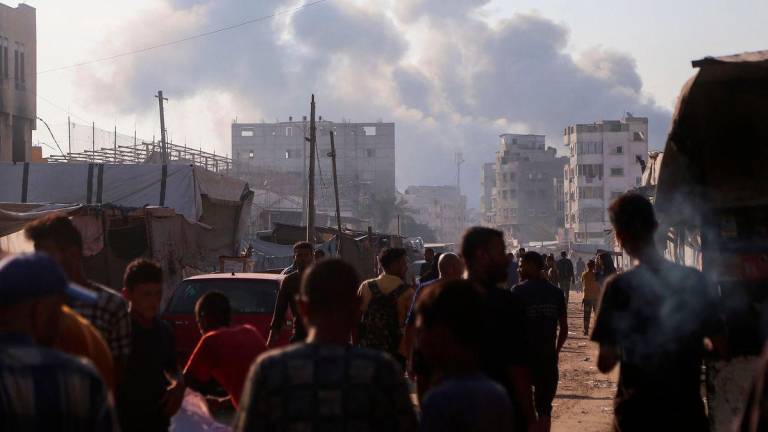 Displaced Palestinians look at smoke billowing amid Israeli strikes on central Khan Yunis in the southern Gaza Strip on July 22, 2025. (Photo by AFP)