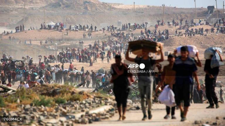 People walk with bags of humanitarian aid they received at a distribution centre run by the US and Israeli-backed Gaza Humanitarian Foundation (GHF), at the so-called Netzarim corridor, in Nuseirat in the central Gaza Strip, on September 26, 2025. - AFP
