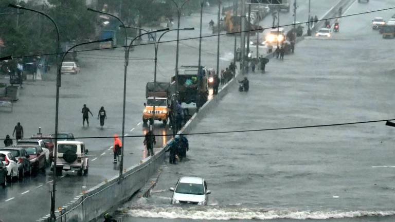 Commuters make their way through a flooded road after heavy rains in Chennai on December 4, 2023. Cyclone Michuang is expected to make landfall on December 5 along the southern coast/AFPPix