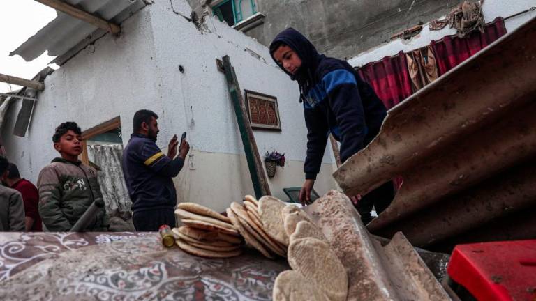 A young man salvages bread loaves from a damaged house, following overnight Israeli bombardment in Rafah in the southern Gaza Strip on February 25, 2024, amid continuing battles between Israel and the Palestinian militant group Hamas. - AFPPIX