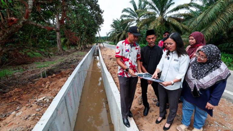 Timbalan Menteri Komunikasi merangkap Ahli Parlimen Kulai, Teo Nie Ching (dua dari kanan) meneliti pelan projek bersama Ketua Kampung Melayu Bukit Batu, Salehan Mansor (dua dari kiri) dan Penghulu Mukim Bukit Batu, Mohamad Norzaharuddin Kasimon (kiri) semasa Lawatan Tapak Projek Banjir di Jalan Masjid, Kampung Melayu Bukit Batu, hari ini.- fotoBERNAMA