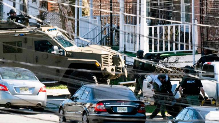 Police evacuate a person (L bottom) from a home in Trenton New Jersey, on March 16, 2024, after reports of a gunman, who is suspected of a shooting spree in Pennsylvania, was barricaded in the house/AFPPix