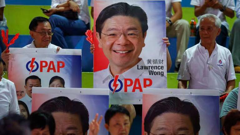 People’s Action Party supporters hold signs in support of Singapore’s Prime Minister Lawrence Wong, as they gather at an assembly area to wait for results of the general election in Singapore - REUTERSpix