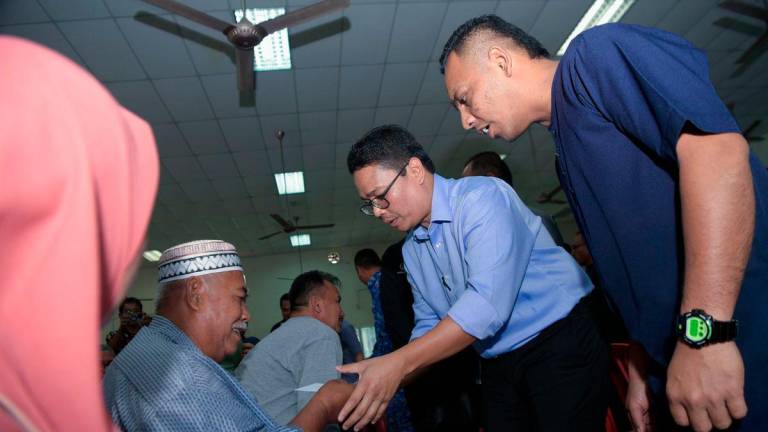 Special Officer to the Menteri Besar for the Kampung Gajah State Legislative Assembly (DUN), Khairul Azwan Harun (second, right), presents aid to recipients at the Perak Tengah District Wang Ihsan Financial Aid Handover Ceremony at the Felcra Seberang Perak Community Hall today. Also present was Pasir Salak UMNO Youth Chief, Mohd Yafiz Mohamad Mustapa (right). - BERNAMA