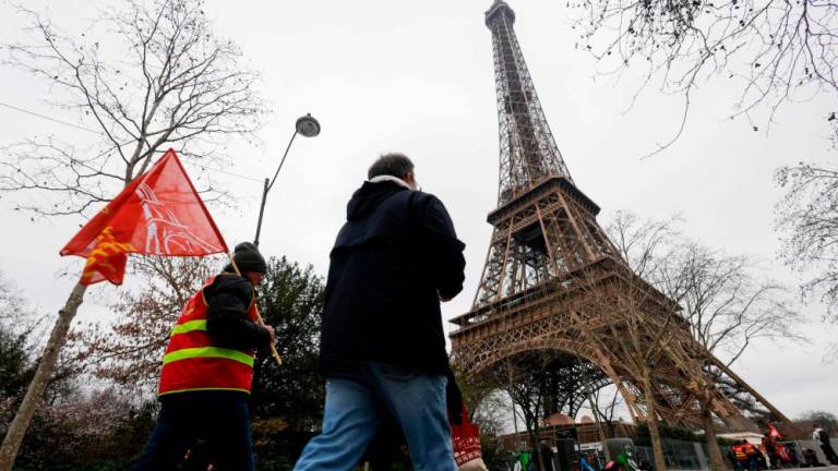Protestors hold CGT unions flags with the Eiffel Tower in the background, during a strike of the Eiffel Tower’s staff, over the financial management of the monument by the city, closing the monument to the public during the second week of the French school holidays, in Paris on February 20, 2024/AFPPix
