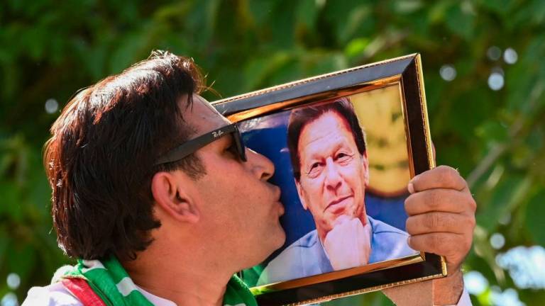 A supporter of Pakistan Tehreek-e-Insaf (PTI) party kisses a photo frame of former Prime Minister Imran Khan, takes part in a protest rally for the release of leader Imran Khan, in Peshawar on March 31, 2024/AFPPix