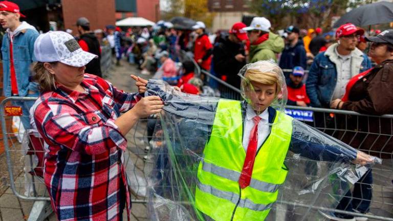 Kruz Chamberlain’s mom helps him put on a rain cover as people wait in line outside the venue where Republican presidential nominee and former U.S. President Donald Trump is expected to hold a campaign rally in Grand Rapids, Michigan, U.S. Reuterspix