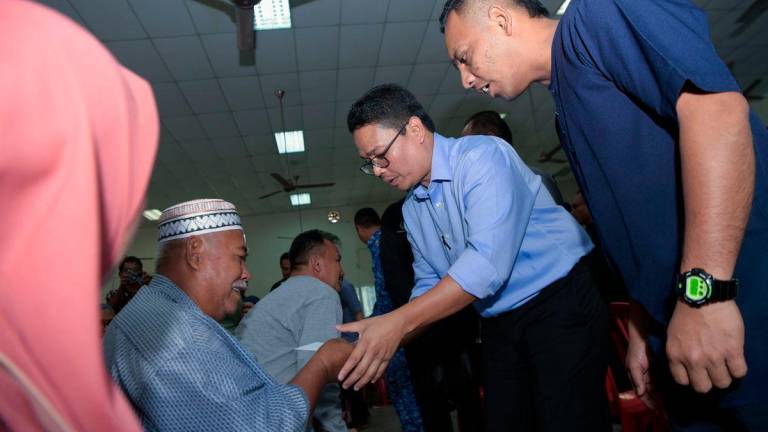 Pegawai Khas Menteri Besar Dewan Undangan Negeri (DUN) Kampung Gajah Khairul Azwan Harun (dua, kanan) menyampaikan bantuan kepada para penerima pada Penyerahan Bantuan Wang Ihsan Daerah Perak Tengah di Dewan Orang Ramai Felcra Seberang Perak hari ini - BERNAMA