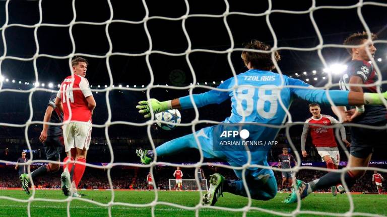 Olympiakos' Greek goalkeeper #88 Konstantinos Tzolakis reaches to save a shot from Arsenal's Norwegian midfielder #08 Martin Odegaard during the UEFA Champions League, league phase football match between Arsenal and Olympiacos at the Emirates Stadium in north London on October 1, 2025. - AFP