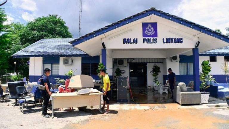 Anggota polis mengangkat barangan pejabat yang rosak selepas ditenggalami air dalam kejadian banjir ketika tinjauan di Balai Polis Lintang hari ini.- fotoBERNAMA