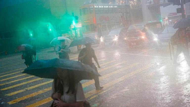 Pedestrians walk past a flooded area during heavy rains, in Hong Kong, China, August 5, 2025. - REUTERSPIX