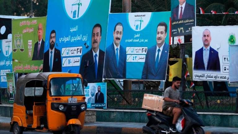 People drive their vehicles past electoral billboards on a street in Baghdad on October 14, 2025, ahead of parliamentary elections on November 11. - AHMAD AL-RUBAYE / AFP