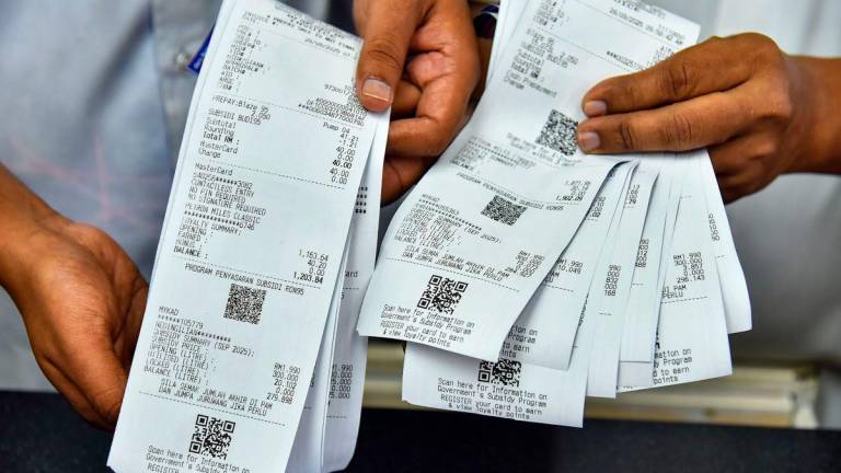A Petron petrol station employee displays a receipt for the purchase of subsidised RON95 petrol at the price of RM1.99 per litre, compared to the current market price of RM2.05 per litre, made by a subsidy recipient today. – BERNAMA