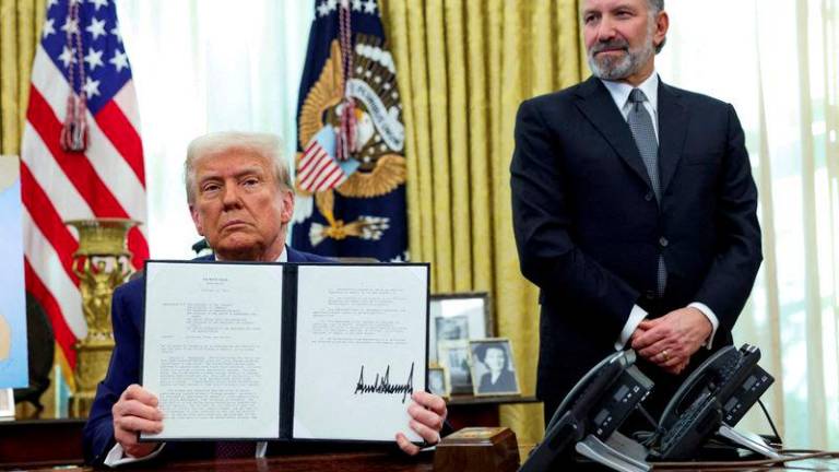 U.S. President Donald Trump holds an executive order about tariffs increase, flanked by U.S. Commerce Secretary Howard Lutnick, in the Oval Office of the White House in Washington, D.C., U.S., February 13, 2025. - REUTERSPIX