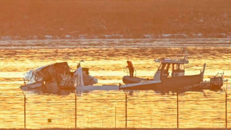 Part of the wreckage is seen as rescue boats search the waters of the Potomac River after a plane on approach to Reagan National Airport crashed into the river near Washington - AFPpix