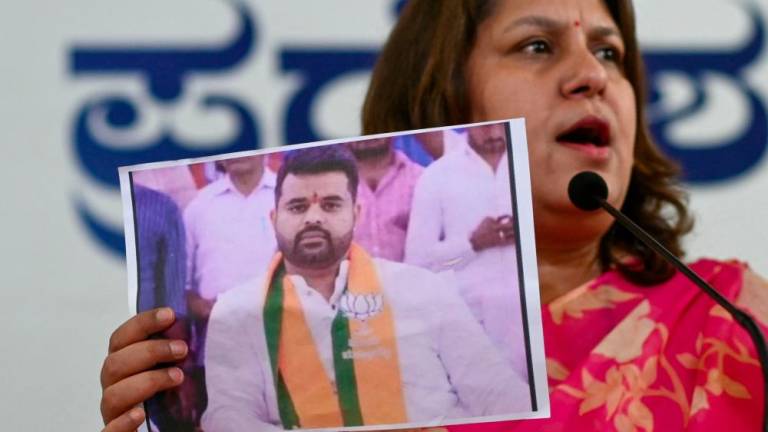 Congress spokesperson Supriya Shrinate shows a photograph featuring JD(S) MP Prajwal Revanna (L) who was summoned for alleged sexual abuse case, at a press conference in Bengaluru on May 1, 2024. - AFPPIX